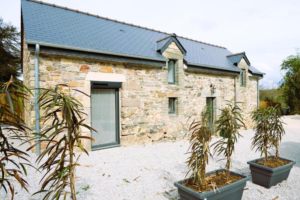 a stone building with two potted plants in front of it at Maison de vacances avec SPA in Martinvast