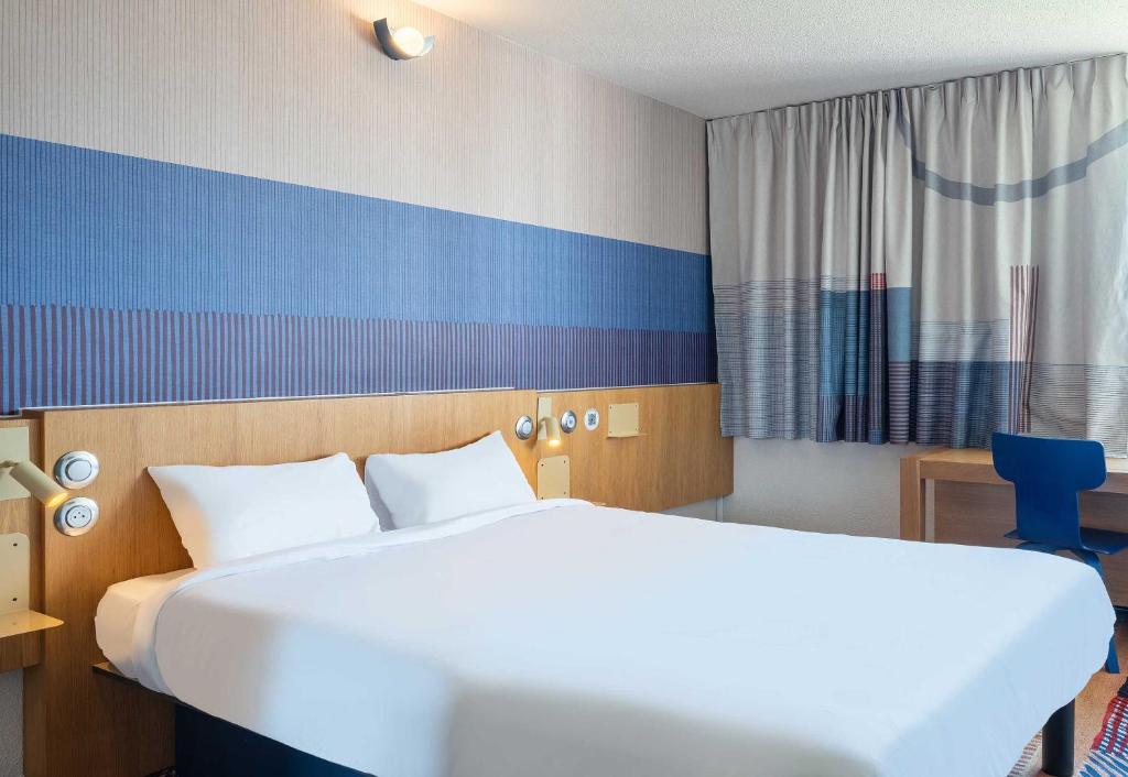 - une chambre avec un grand lit blanc et un mur bleu dans l'établissement B&B HOTEL Saint-Pierre-en-Faucigny Bonneville, à Saint Pierre en Faucigny