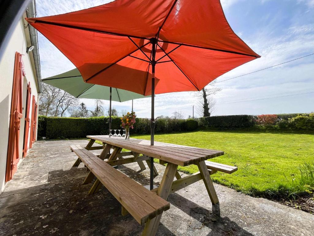 - une table de pique-nique avec un parapluie rouge dans l'établissement Le Gîte de LiliRose, à Cricqueville-en-Bessin