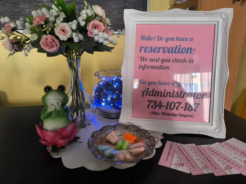 a table with a sign and a vase with flowers at Willa Retro Hostel & Garden in Kraków