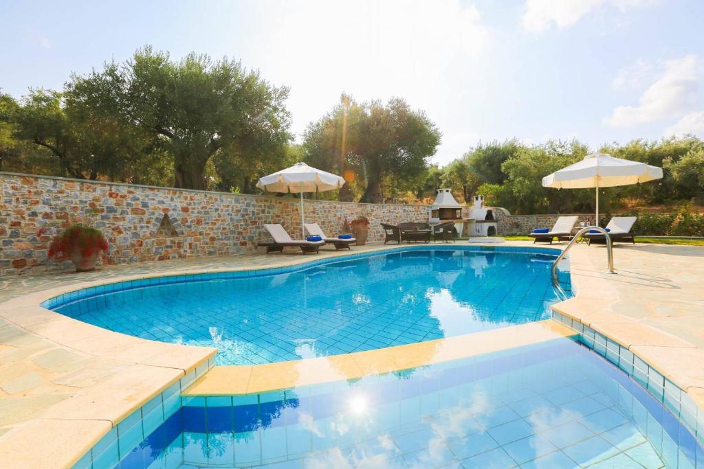 une piscine avec chaises et parasols dans l'établissement Villa Selini at Sunset Villas, à Skiathos Chora
