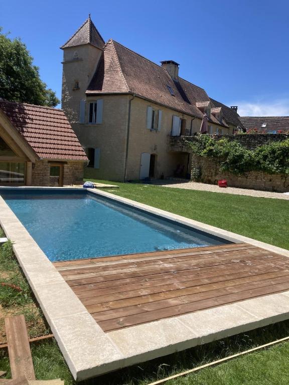 une piscine avec une terrasse en bois devant une maison dans l'établissement Maison de charme - Piscine chauffée - Bouzic, à Bouzic