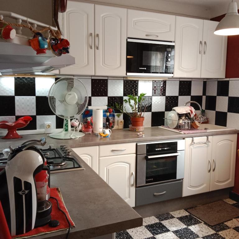 une cuisine avec des armoires blanches et du carrelage noir et blanc dans l'établissement Grand Appartement T2 avec parking et clim à 50m de la Plage centrale !, à Canet