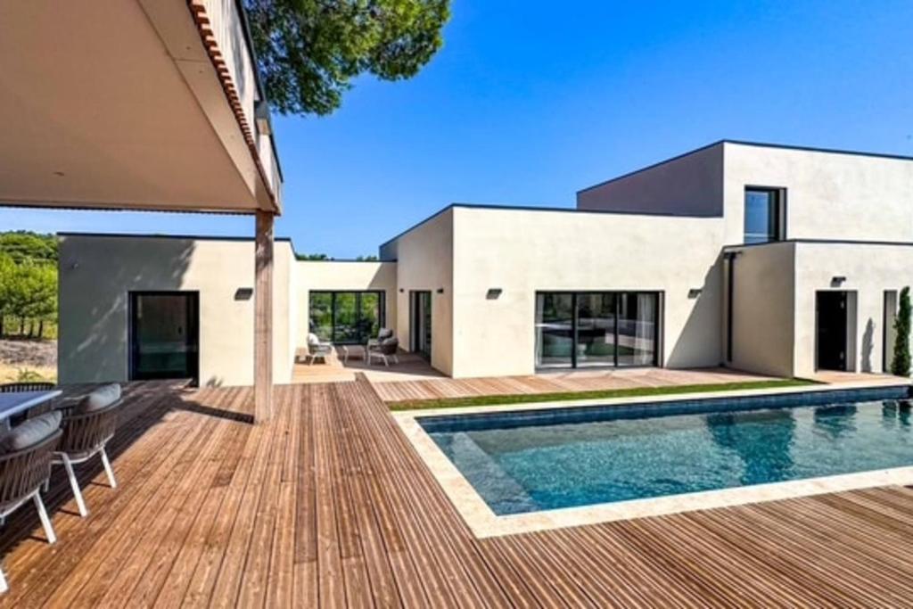 une maison avec une piscine et une terrasse en bois dans l'établissement Villa Pineda - Luxe Piscine & Nature, à Lézignan-Corbières