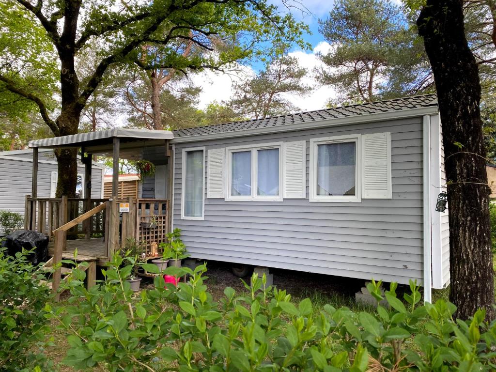 une petite maison avec une terrasse couverte dans une cour dans l'établissement Mobil Home cosy 5 personnes proche du Puy Du Fou, à La Boissière-de-Montaigu
