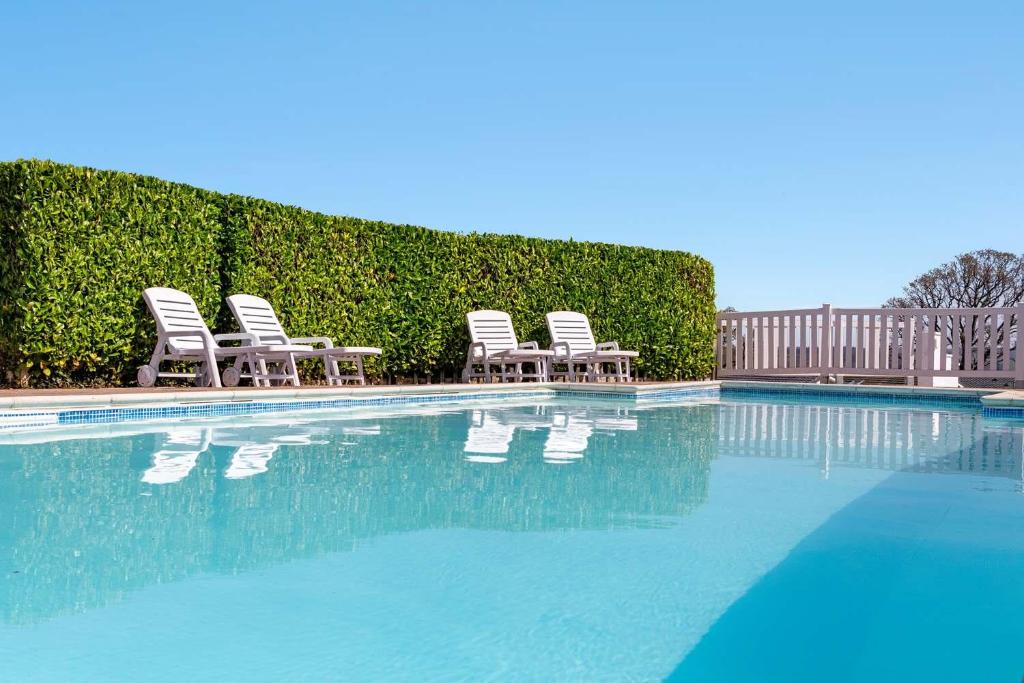 a group of chairs sitting next to a swimming pool at Springfield Deer View - Private Hot Tub , 2 Dogs Max,Fishing Nearby & Communal Swimming Pool ,Shut for the winter open April 2026 in Cheriton Bishop