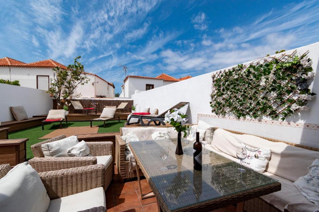 a patio with a table and chairs and a white wall at Villa Tricia 6 Bedroom Las Americas in Playa de las Americas