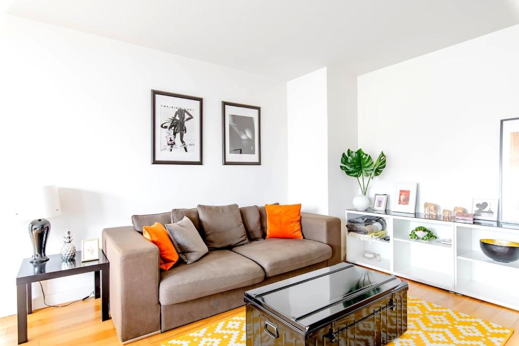 - un salon avec un canapé brun et des oreillers orange dans l'établissement Lyon 8 Beautiful, bright and quiet apartment, à Lyon