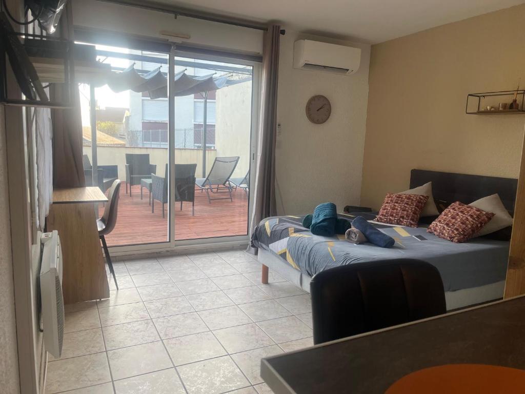 une chambre avec deux lits et un balcon avec une table dans l'établissement Rare en centre ville, studio climatisé avec terrasse XXL, à Tarbes