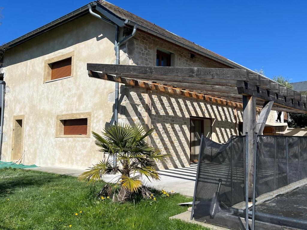 une maison avec un toit en bois et un palmier en face de celle-ci dans l'établissement La Grange de Jannine et Clémentine, à Saint-Germain-la-Chambotte