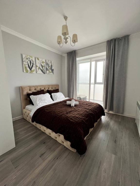 a bedroom with a large bed with a brown blanket at В центре апартаменты ЖК Orynbor Towers in Astana