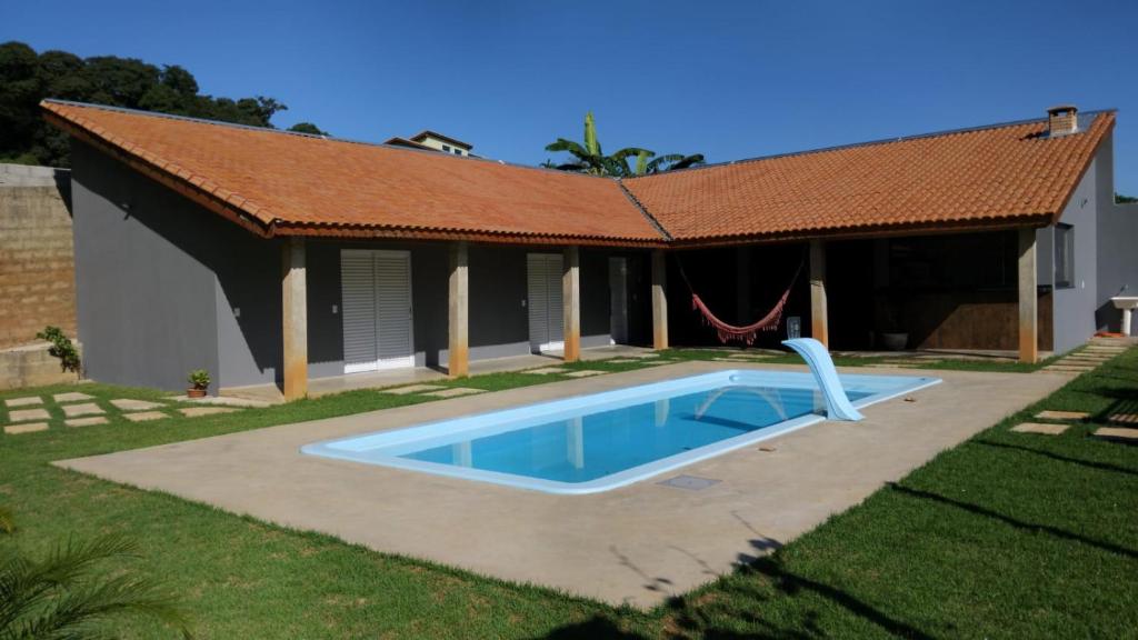 a house with a swimming pool in the yard at Recanto dos Mineiros in Monte Alegre do Sul