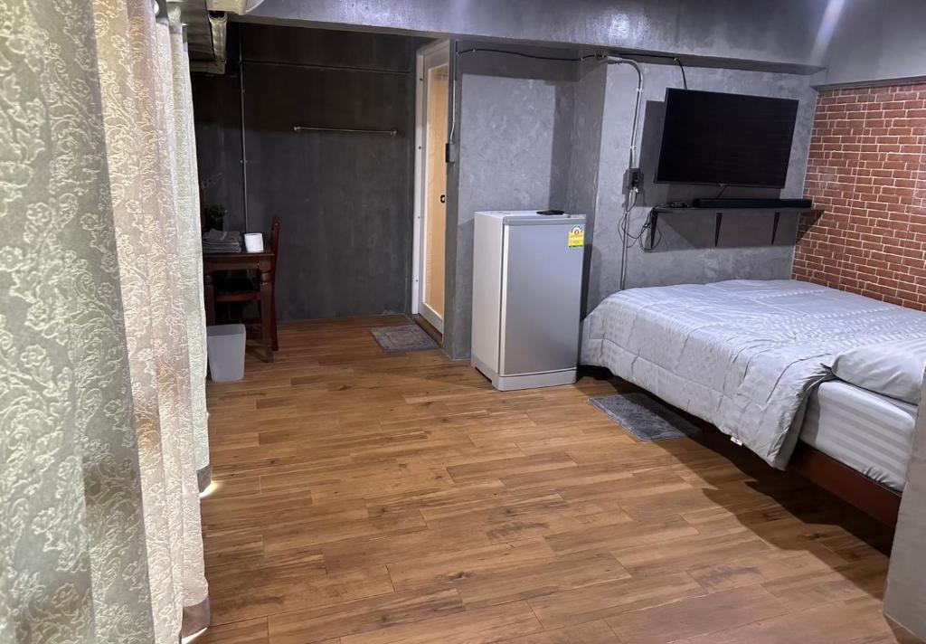 a bedroom with a bed and a small refrigerator at Kai guesthouse in Ban Nong Chaeng