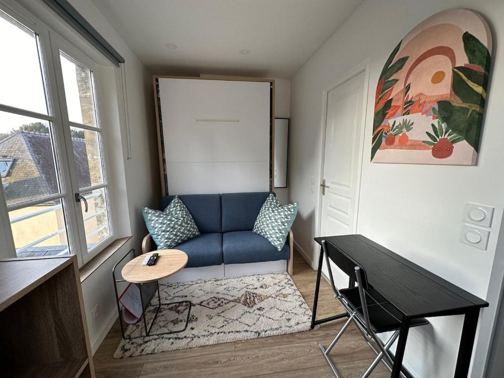 un salon avec un canapé bleu et une table dans l'établissement Le nid de la cathédrale, à Bayeux