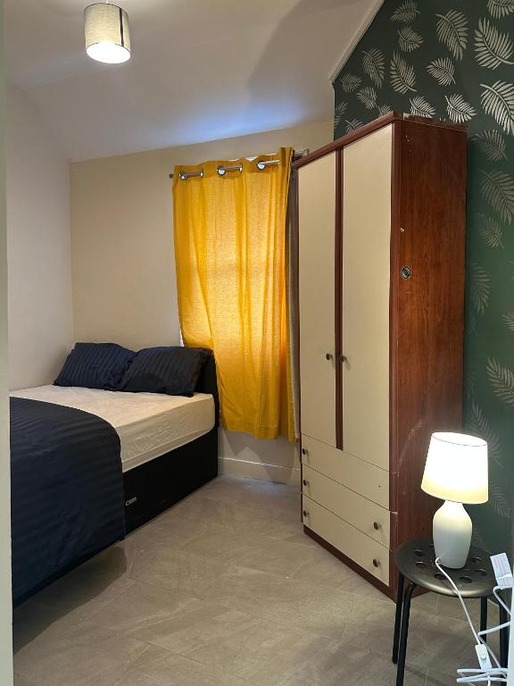 a bedroom with a bed and a yellow curtain at Parkend Room Stays in Oxford