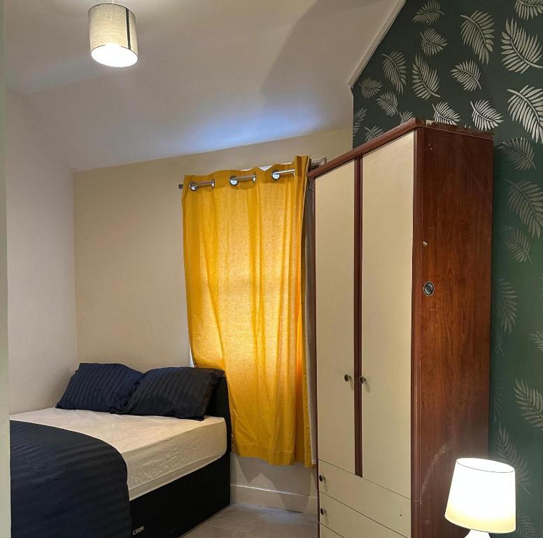 a bedroom with a bed and a yellow curtain at Parkend Room Stays in Oxford