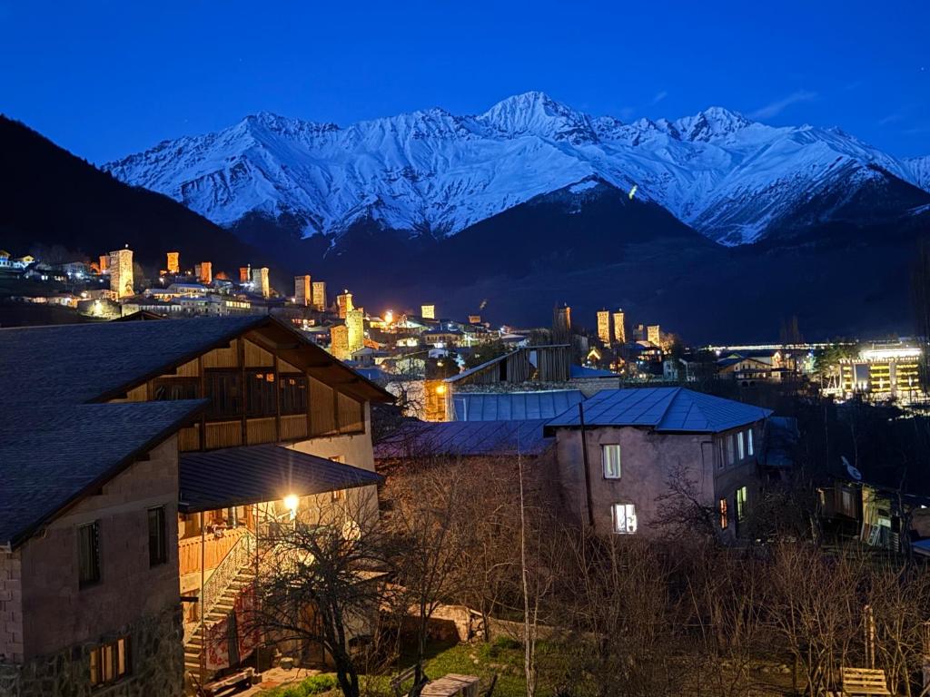 a city with snow capped mountains in the background at Hotel Elite House in Mestia