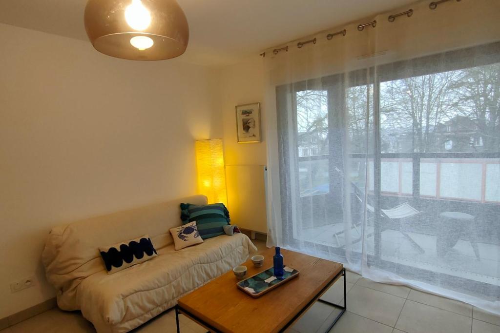un salon avec un canapé, une table et une fenêtre dans l'établissement 1-bedroom apartment in residence, à Dinard