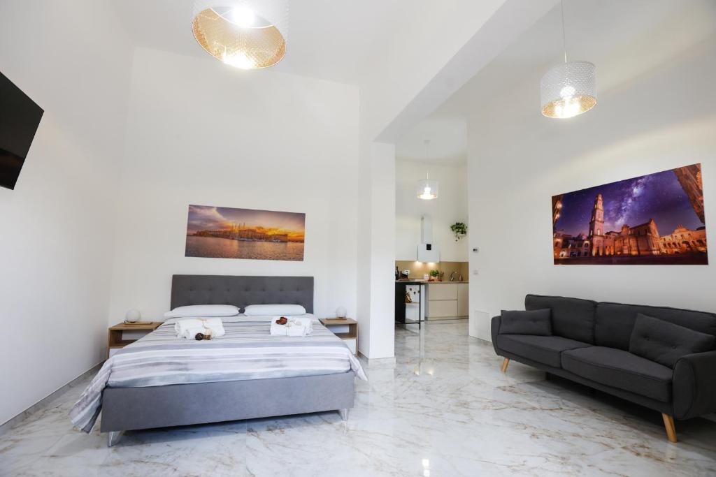 una camera da letto bianca con un letto e un divano di Elegante Suite con giardino nel centro Lecce - Free Parking - WiFi a Lecce