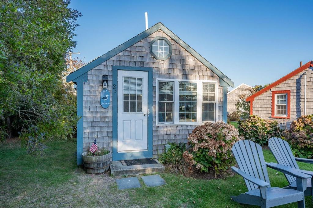 a small house with a blue door and two chairs at Seaside Cottages - Cottage 23 - SeaGills Rest in South Yarmouth