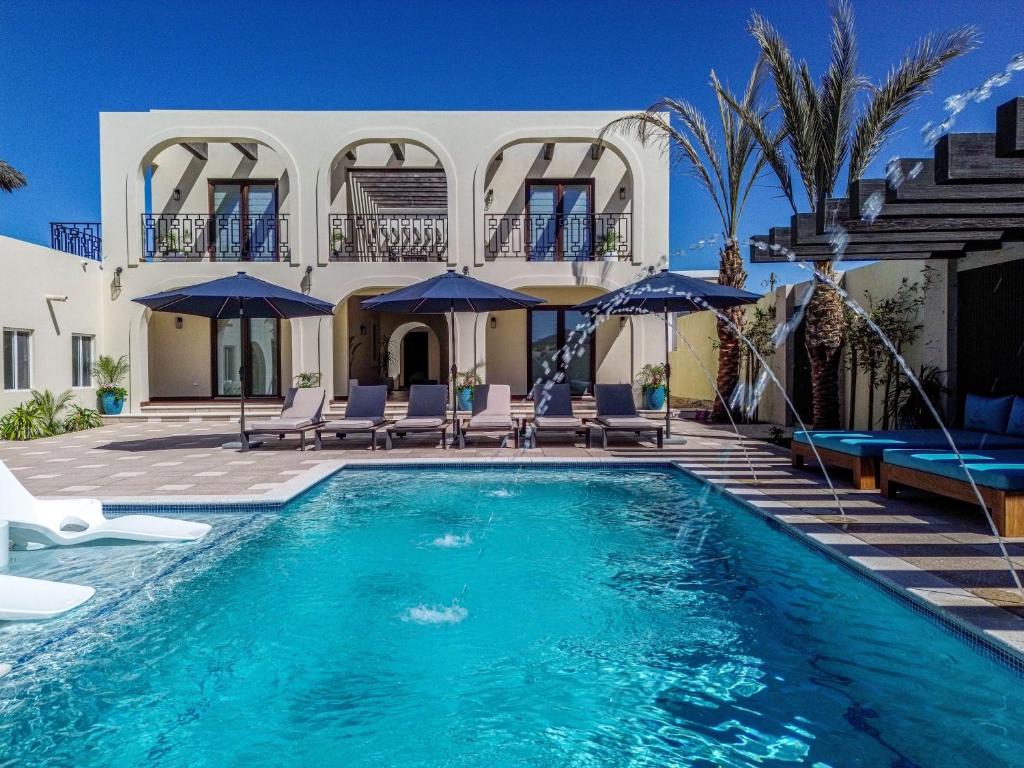 ein Pool mit Stühlen und Sonnenschirmen vor einem Haus in der Unterkunft Paz del Mar 24 guests in Puerto Peñasco