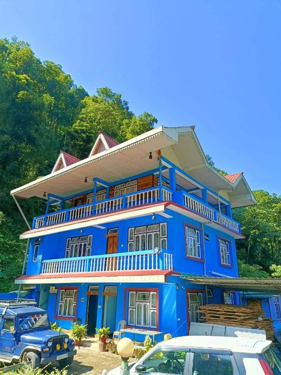 a blue building with cars parked in front of it at Sisney River Retreat in Rongli
