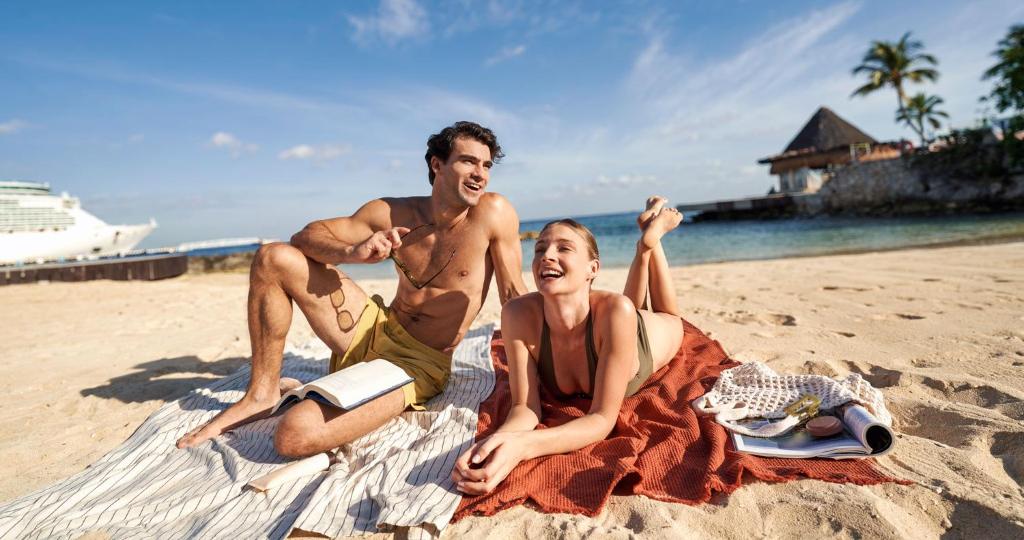 a man and a woman sitting on the beach at Grand Park Royal Cozumel - All Inclusive in Cozumel