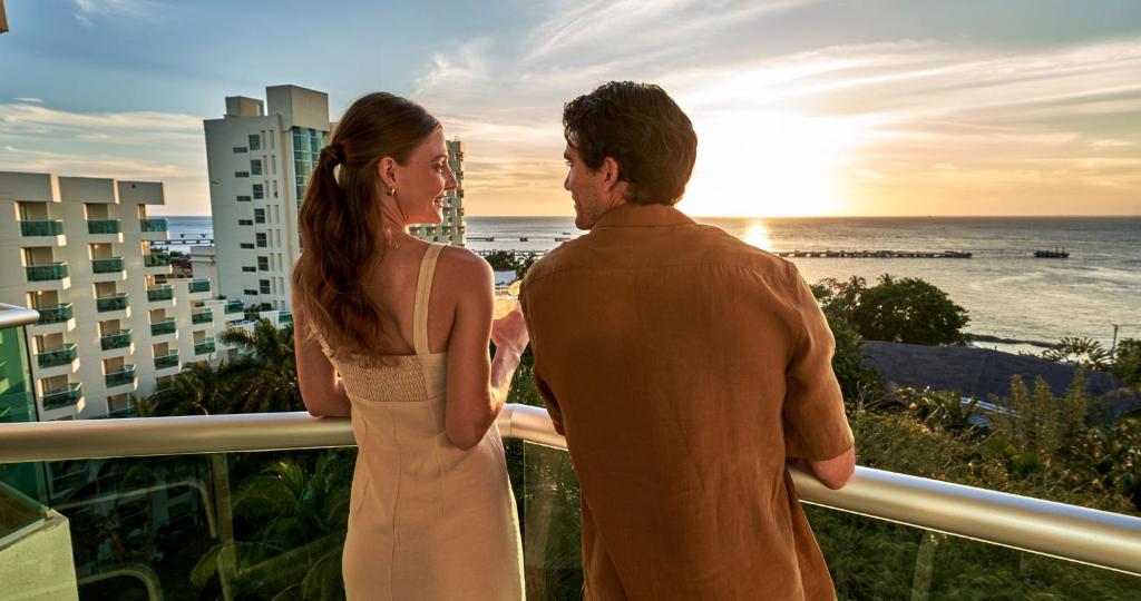 a man and woman standing on a balcony looking at the ocean at Grand Park Royal Cozumel - All Inclusive in Cozumel