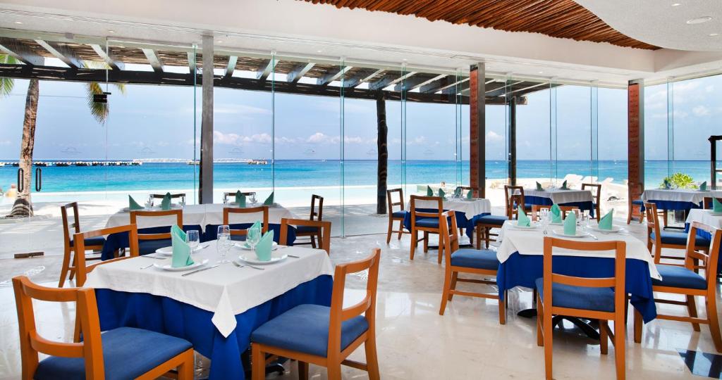 a restaurant with tables and chairs and the ocean at Grand Park Royal Cozumel - All Inclusive in Cozumel