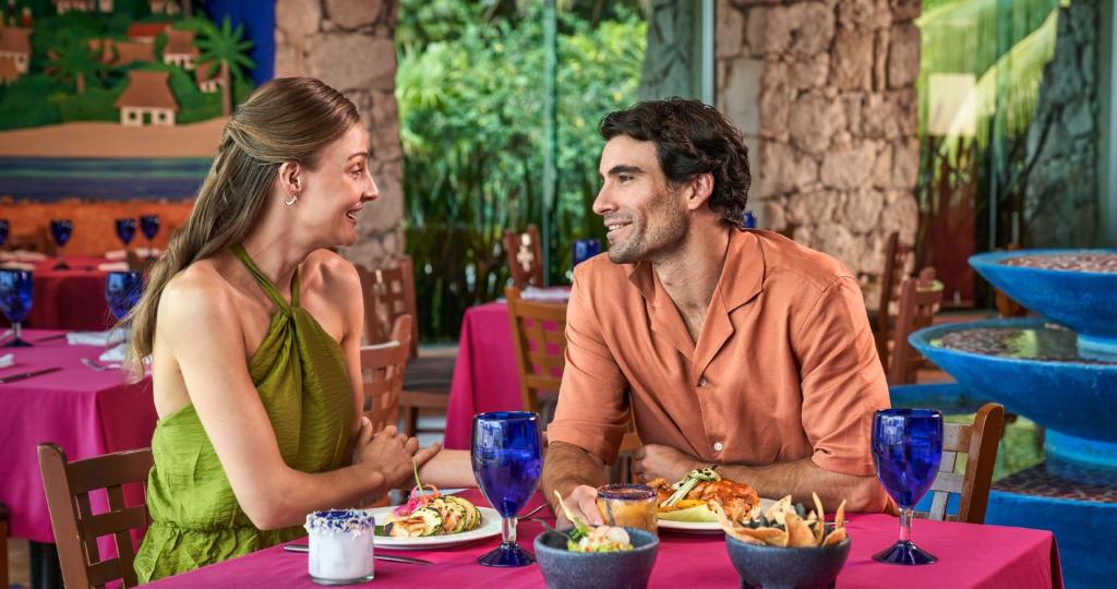 a man and a woman sitting at a table in a restaurant at Grand Park Royal Cozumel - All Inclusive in Cozumel