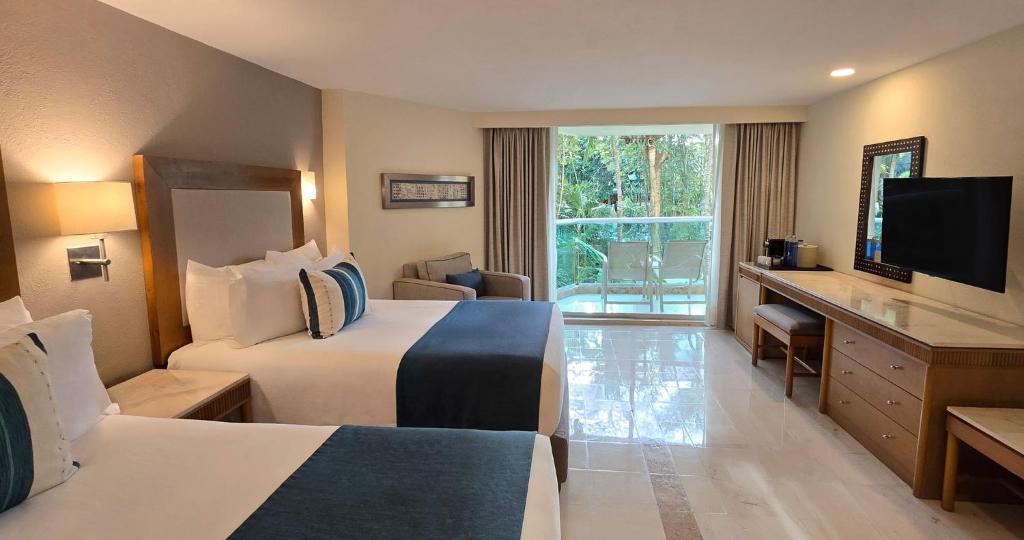 a hotel room with two beds and a flat screen tv at Grand Park Royal Cozumel - All Inclusive in Cozumel