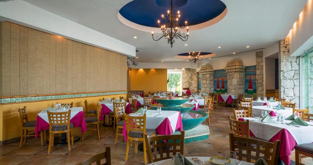 a restaurant with tables and chairs and a chandelier at Grand Park Royal Cozumel - All Inclusive in Cozumel