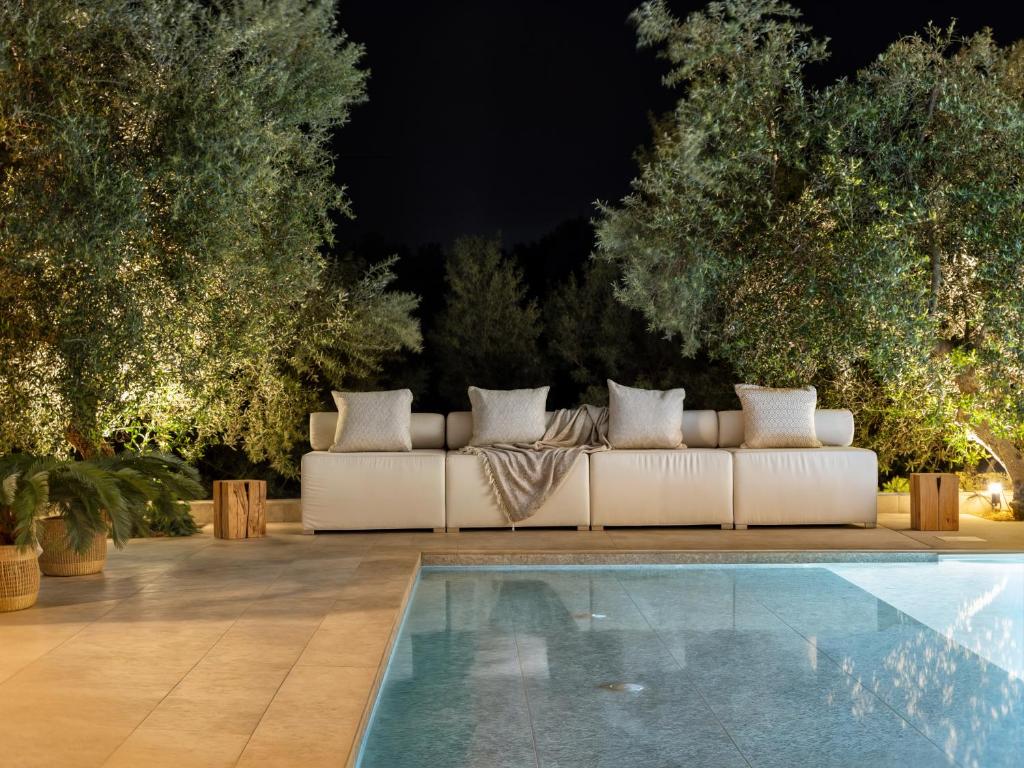 a white couch sitting next to a pool at night at The White Luxury Villa - Private Seaview Villa with Pool by Villa Mana Gers in Vasilikos