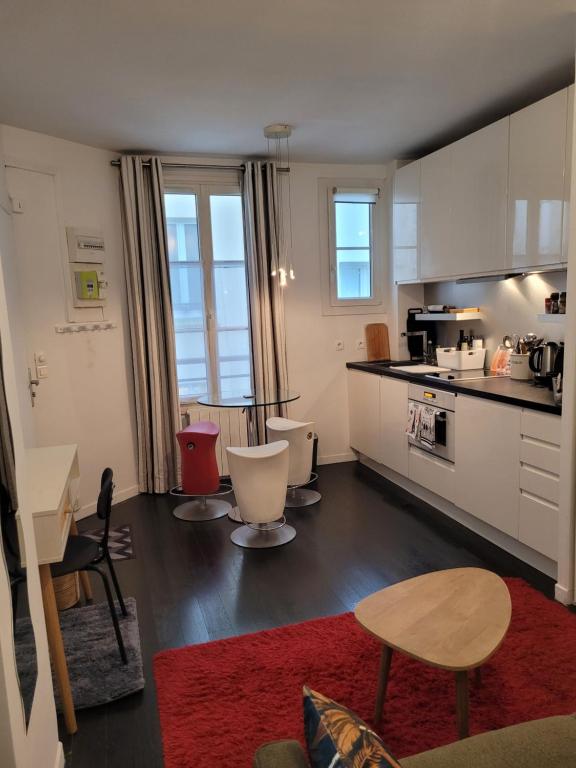 une cuisine avec des armoires blanches et une table et des chaises dans l'établissement Studio calme proche Montmartre et Batignolles - Metro 13 et 14, à Paris