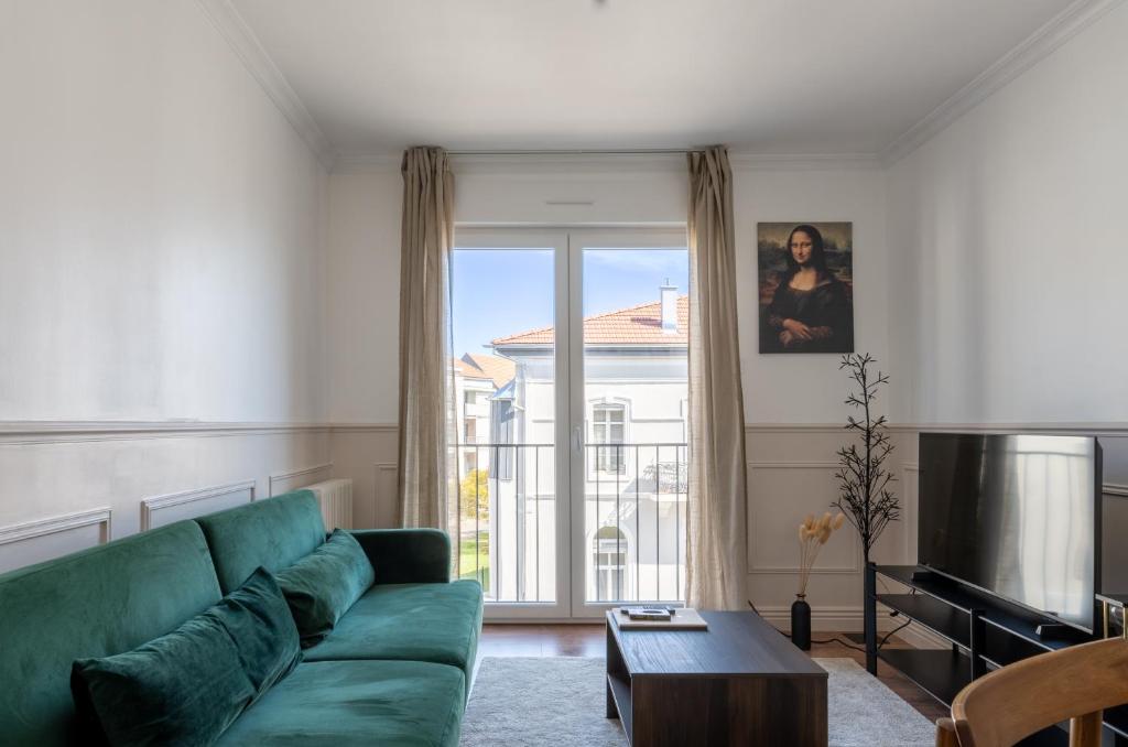 - un salon avec un canapé vert et une grande fenêtre dans l'établissement Le Parisien d'Alsace, à Colmar