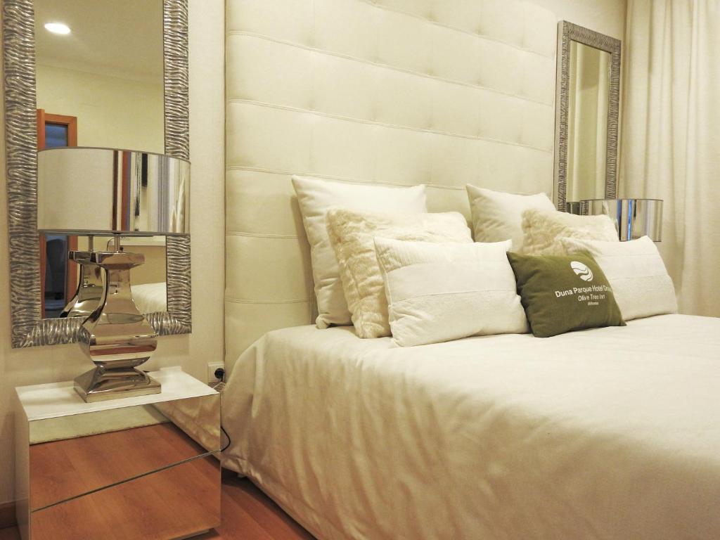 a white bed sitting in a bedroom next to a window at Milfontes Guest House - Duna Parque Group in Vila Nova de Milfontes