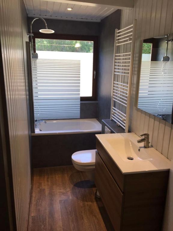 a bathroom with a tub and a toilet and a sink at Chalet le Faye in Waimes
