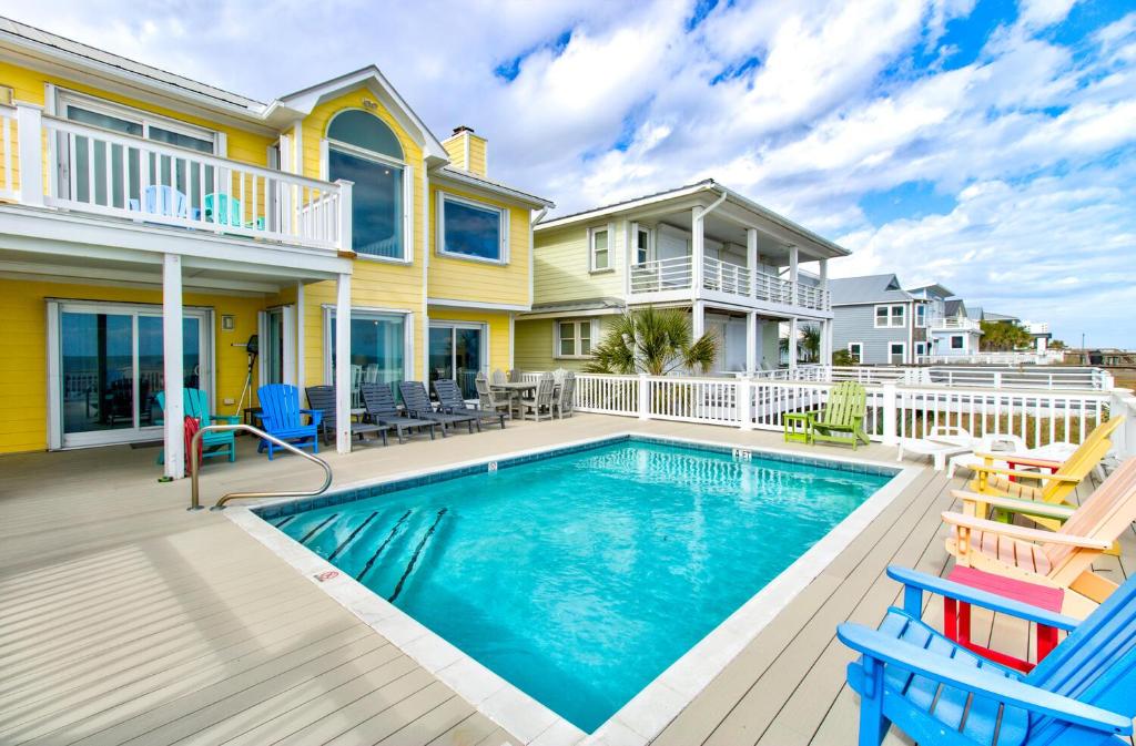 a house with a swimming pool and two chairs at Dolphin Run by Carolina Beach Realty in Kure Beach