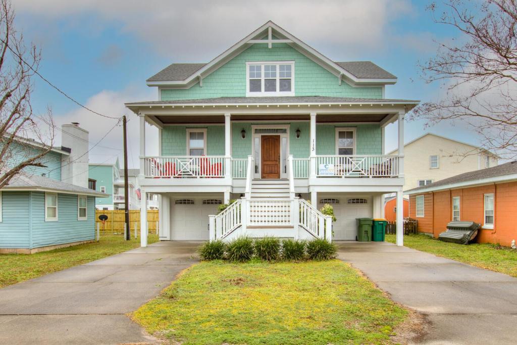 a green house with a white porch at Elanora by Carolina Beach Realty in Kure Beach