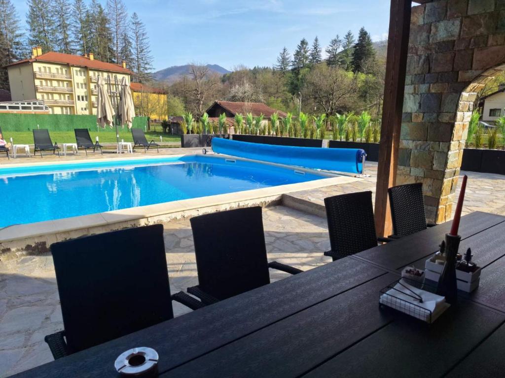 a table with chairs next to a swimming pool at Къща за гости Брязово in Ribarica