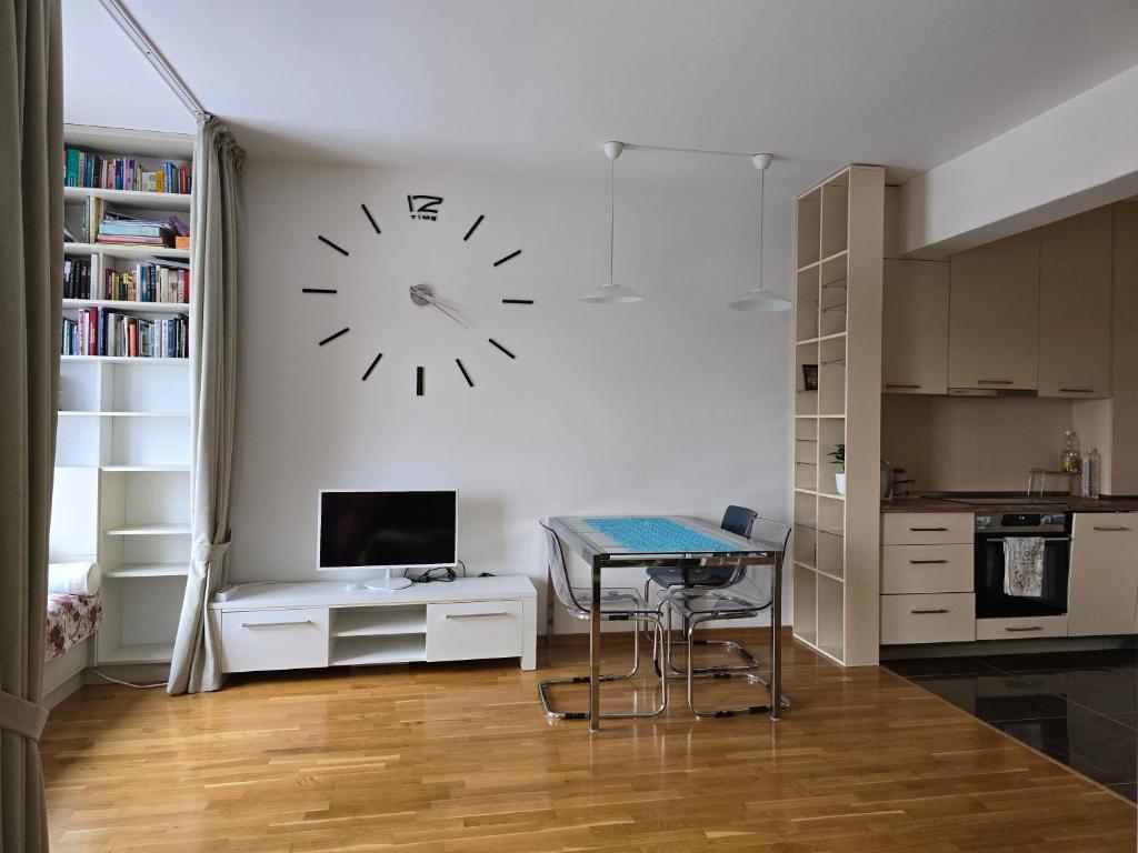 a kitchen with a table and a clock on the wall at Стильная квартира с видом на море и библиотекой in Becici
