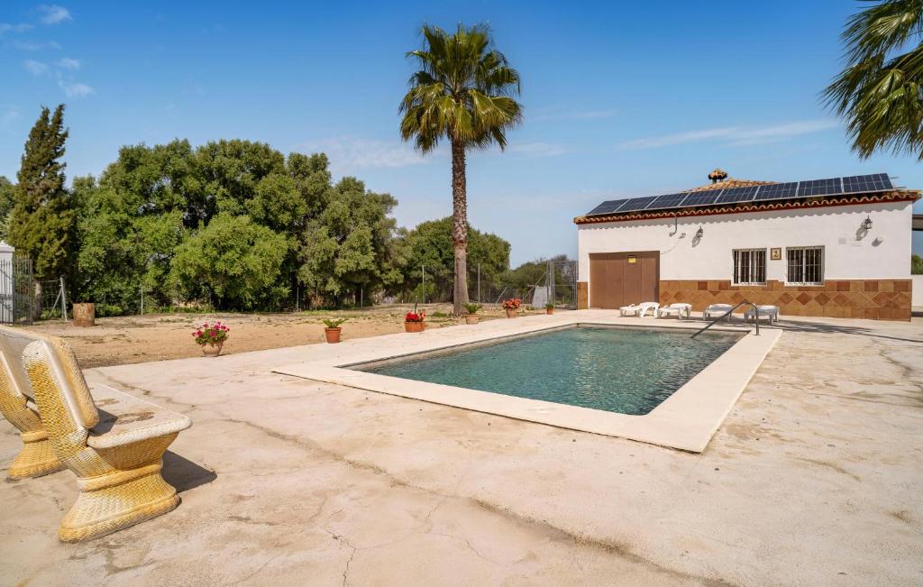 a swimming pool in front of a house with a palm tree at Vistas De La Sierra in Arcos de la Frontera