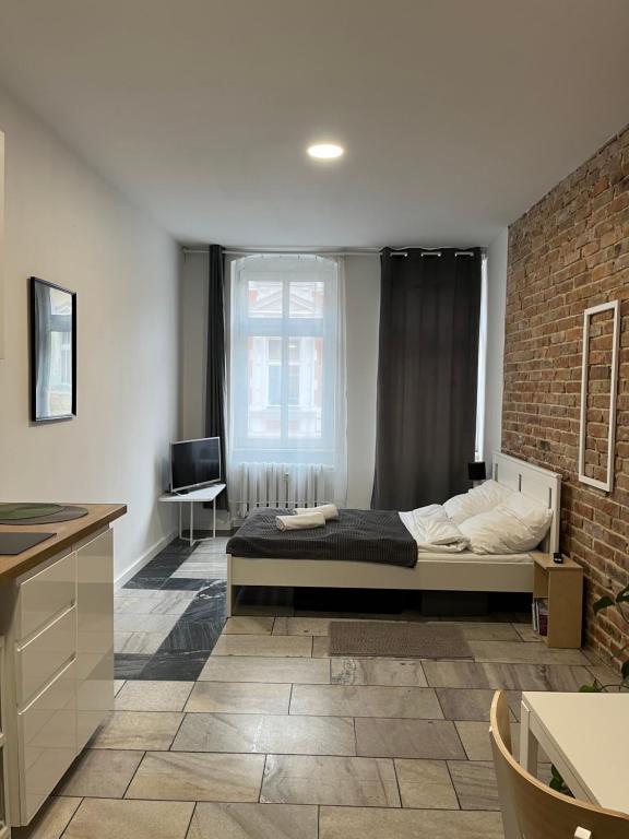 Un dormitorio con una cama y una pared de ladrillo. en Apartament Monstera II- top śniadanie, en Bydgoszcz