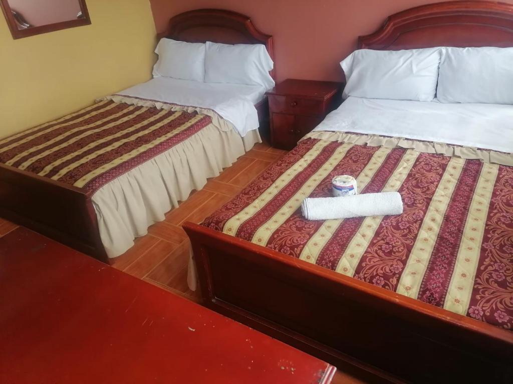 twee bedden in een hotelkamer met een krant op het bed bij Hotel Don Jhon in Estación El Salto