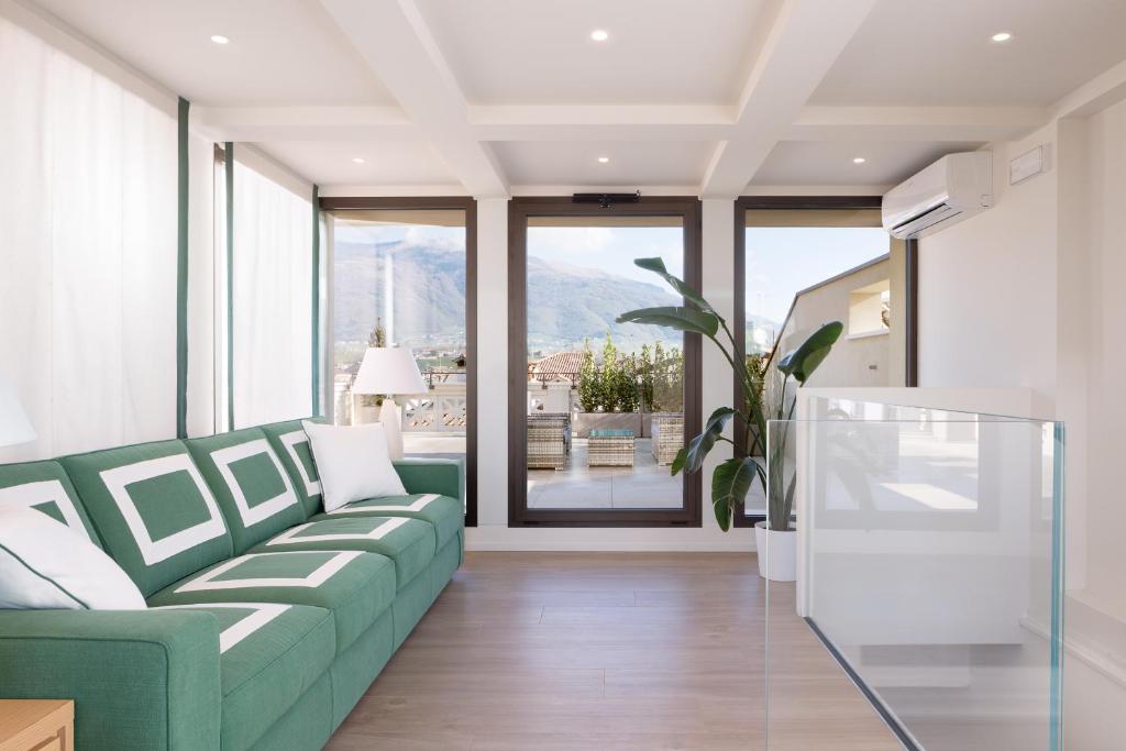 ein Wohnzimmer mit einem grünen Sofa und großen Fenstern in der Unterkunft Bellavista Holiday House in Valdobbiadene