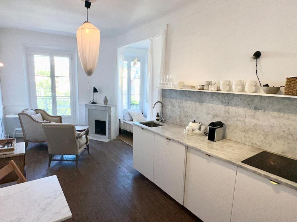 une cuisine avec des armoires blanches et un salon dans l'établissement French classic apartm 2 bedroom best location, à Cannes
