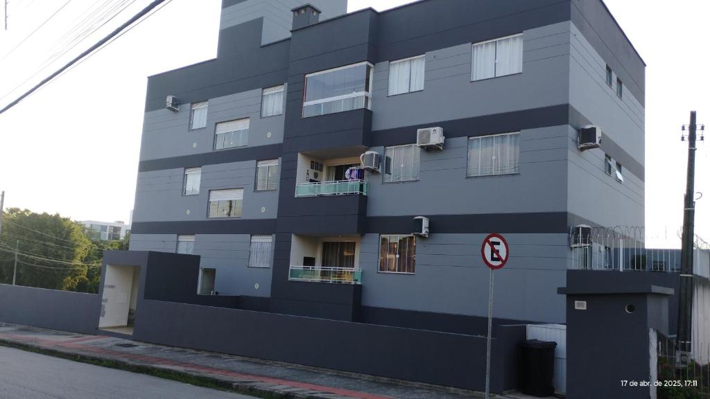 a tall grey building with windows on a street at Apê aconchegante in São José