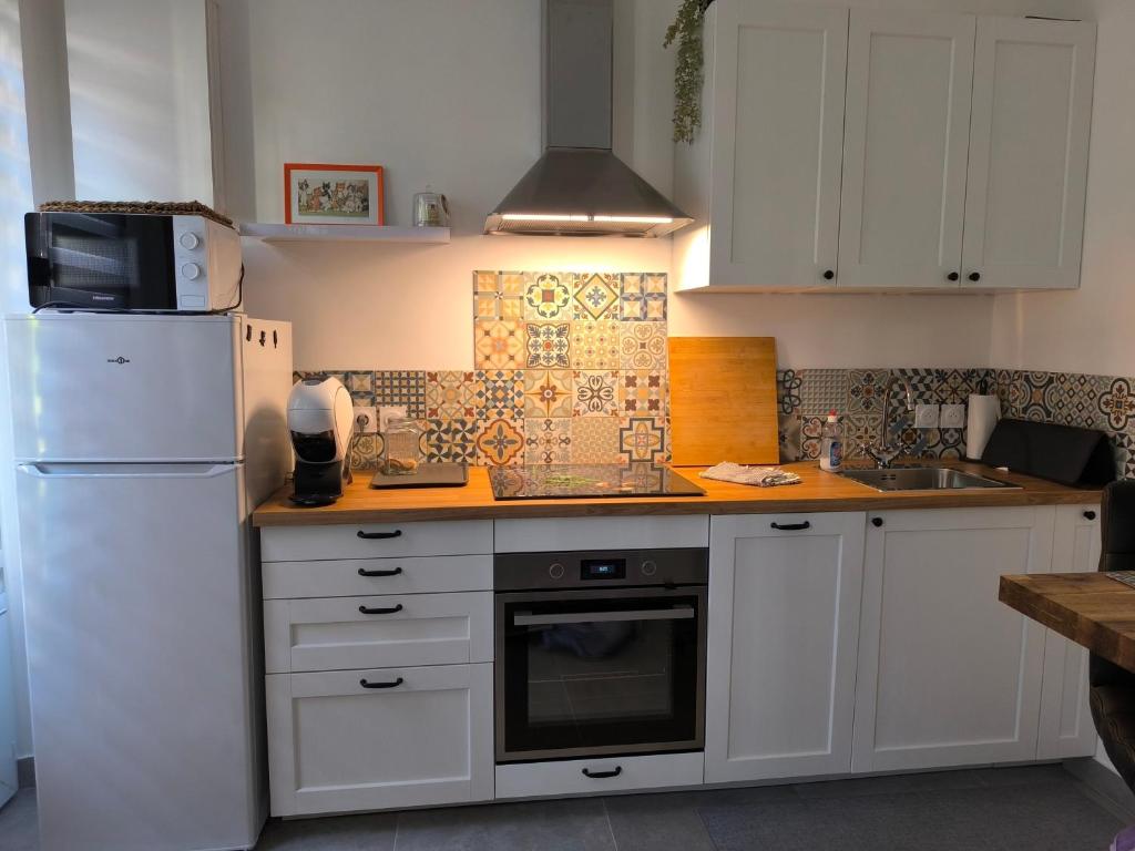 a kitchen with white cabinets and a white refrigerator at Studio "La fleur de Lys" in Ault