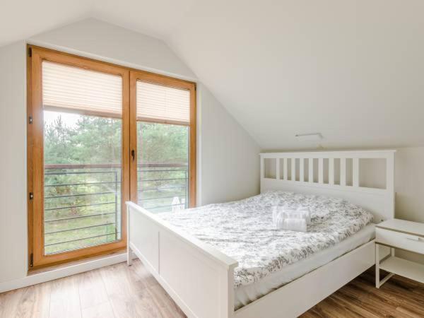 una camera bianca con un letto e una grande finestra di Zagroda ciszy a Lubiatowo