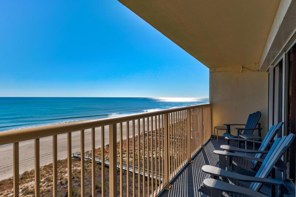 a balcony with blue chairs and the beach at Pelican Watch 706: Sea You Next Time by Carolina Beach Realty in Carolina Beach